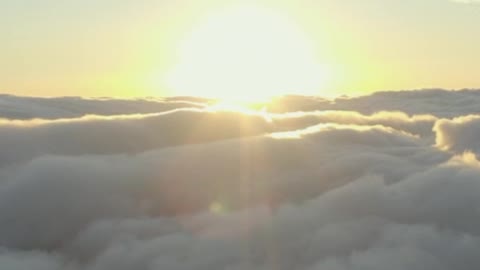 The sun setting on the horizon of a cloudy mountain range