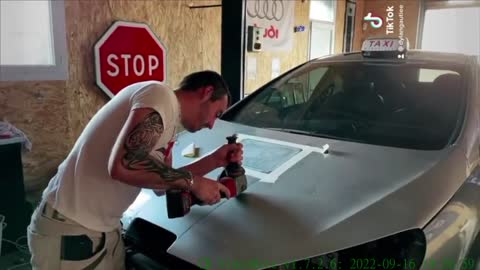A worker repairs the hood of a car
