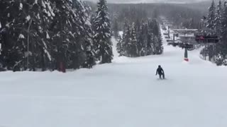 Snowboarder purple jacket falls backwards on hill
