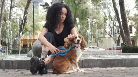 Girl sitting at a fountain with her dog aside