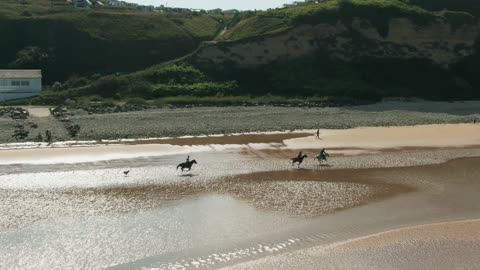 Aerial Footage Of Men Enjoying Horseback Riding Along The Seashore