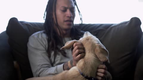 Young African American Man with Dreadlocks Playing with his Puppy