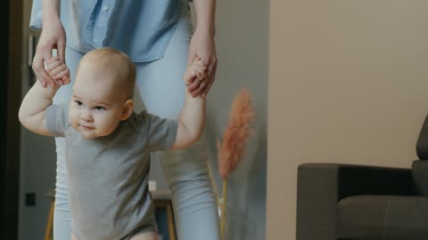 The baby begins to walk with his beautiful mother.