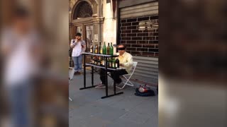 Blindfolded street performer plays music on bottles
