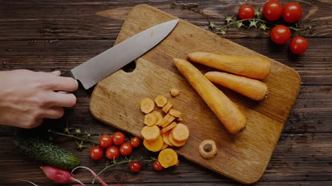 A Person Cutting a Carrot Into Slices by Using a Knife