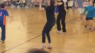 Girl in black misses basketball pass and then falls face first onto floor