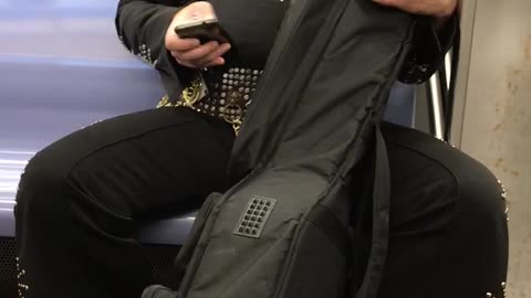 Man with elvis costume carrying large instrument case