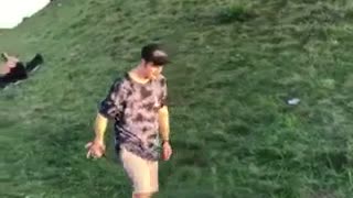 Guy in black hat and blue tie dye shirt fail front flip on grass