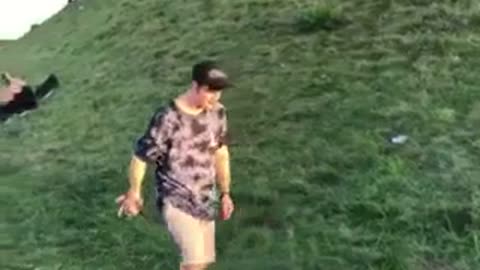 Guy in black hat and blue tie dye shirt fail front flip on grass