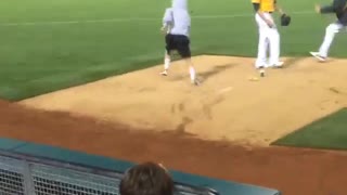 Guy hops fence and runs on baseball field