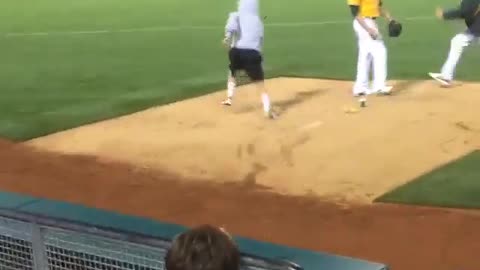 Guy hops fence and runs on baseball field