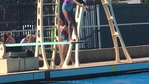 Girl in pink jumping into pool belly flops