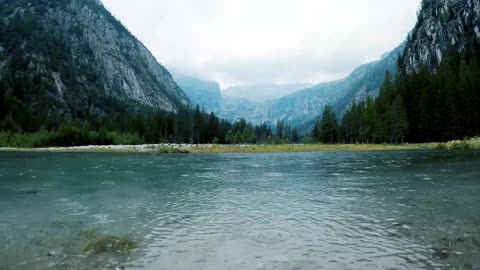 lake surrounded by cloudy mountains - rain in water and thunder