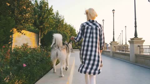 Young female walking with siberian husky dog on sea front