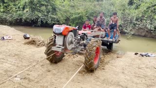 The little driver pulls the tractor from the river