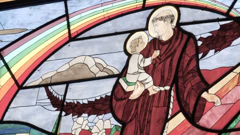 Monk carrying a child depicted in the stained glass window of a church