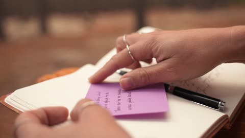 Close up of a Person Sticking a Note in a Notebook