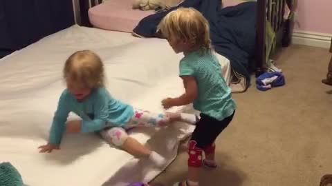 Identical twin toddlers tickle each other