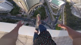 Man Skateboards on Edge of Tall Building