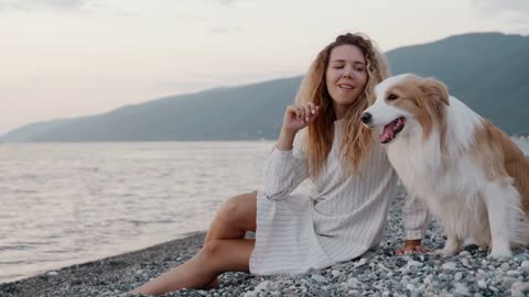 Best friends tender moment. Young curly girl sitting on rocks with her border collie dog