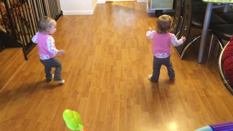 Identical twin babies walk simultaneously together