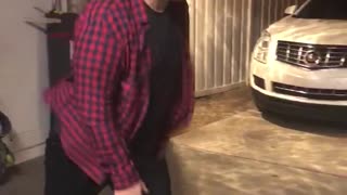 Guy in red shirt does high kick in garage and falls