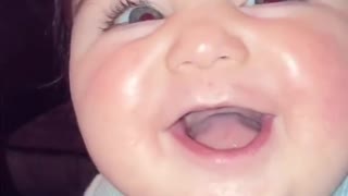 Cute baby with bright blue eyes giggles at mom