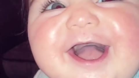 Cute baby with bright blue eyes giggles at mom
