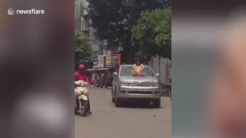 Woman climbs on the car driver tries to shake her off, in rush hour in Vietnam