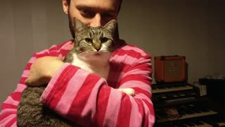 Red striped shirt guy pets brown cat in his hands