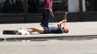 Man plays trumpet on floor of street