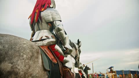 A man knight in helmet with fabric clippings riding a horse on the battlefield