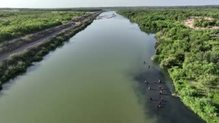 Migrants wade past floating barriers at Texas border