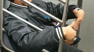 Man waves air into his face with his hands on subway train