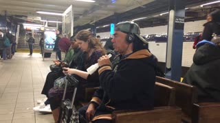 Man uses tube as a microphone and talks to himself at subway station bench