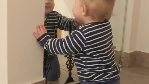 Sweet baby talks to his reflection in the mirror