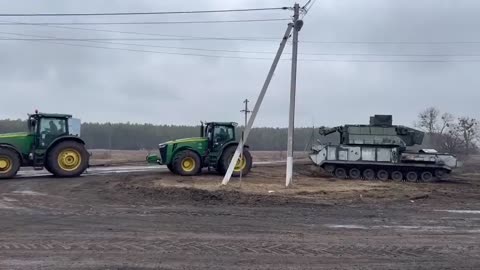 Ukrainian farmers towing an abandoned Russian Tor-M2 short-range air defense system