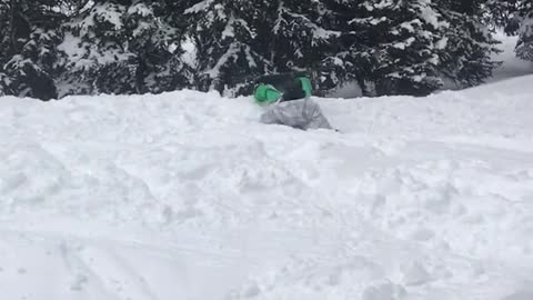 White jacket snowboarder backflips into snowy faceplant