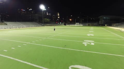 Aerial, athlete stands on football field at night
