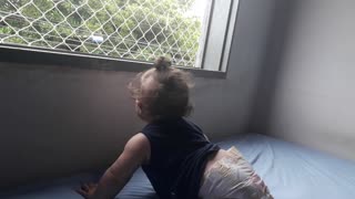 Luninha pequenininha vendo a rua da janela