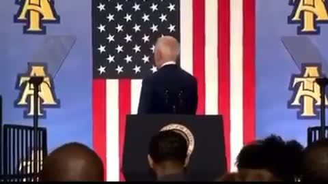 President Joe Biden shaking invisible hand during a speech in North Carolina