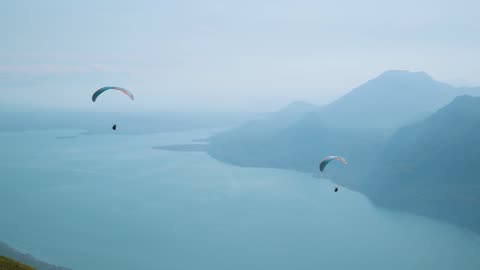 Two Men Fly in The Mountains On Gliders