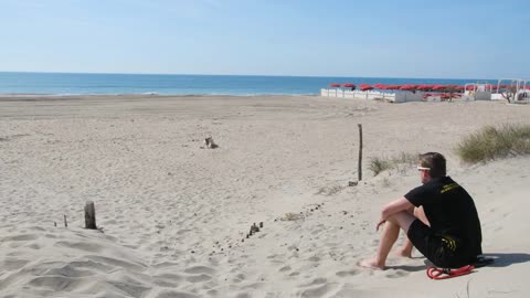 Man playing with his dog on a sandy beach Sete France