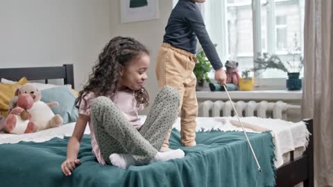 Kids Playing Catch The Bait With Their Cat In The Bedroom