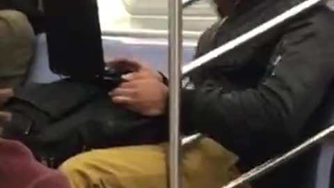 Beanie guy bangs head to laptop on subway