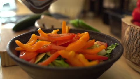 Close Up of Female Hands Adding Sliced Pepper to Salad Bowl