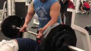 Guy very heavy bench press, bar falls off rack and almost crushes him