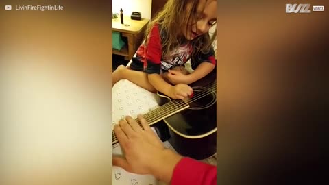 Tender moment when a father and his daughter share a guitar