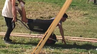 Guy wheelbarrow backyard pretending to paddle swim