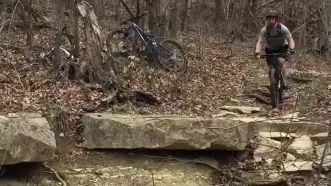Man in grey rides dirt bike falls onto rocks